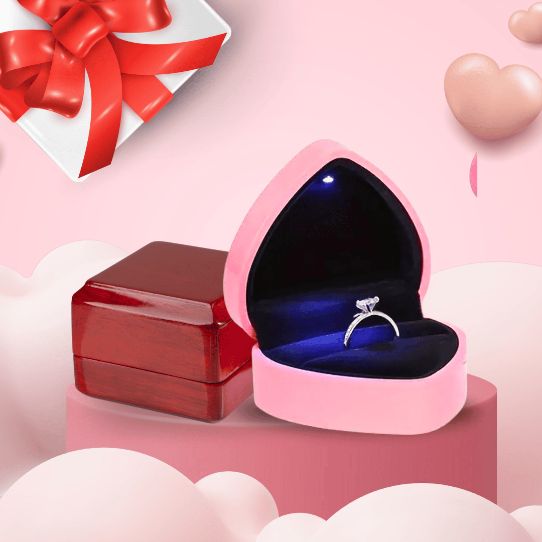 Circular image showcasing elegant ring packaging, featuring a heart-shaped pink box with an LED light illuminating a diamond ring, paired with a classic wooden box. Set against a romantic pink background with cloud and ribbon accents, inviting users to shop ring boxes for special occasions.