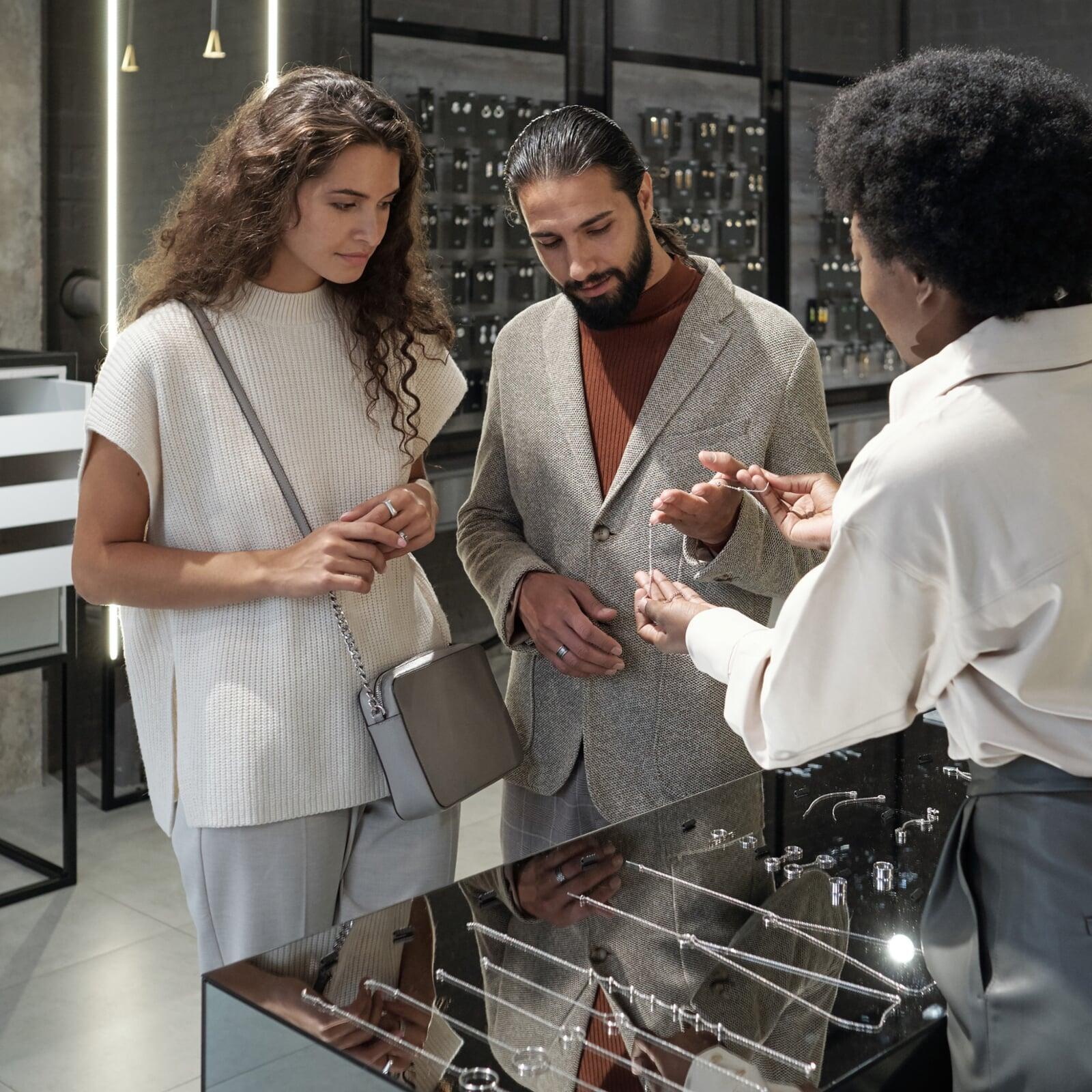 A luxury jewelry event featuring guests admiring high-quality pieces and interactive displays in a beautifully decorated showroom. 